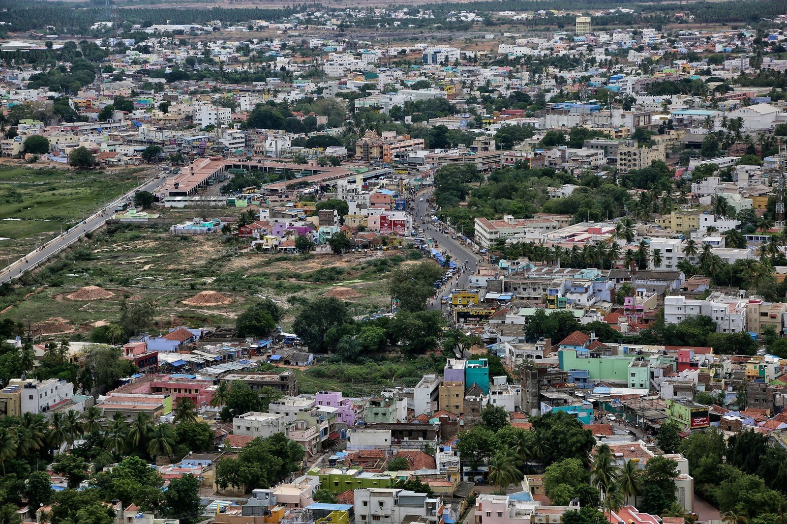 Town of Palani in Tamil Nadu - Pollachi Real Estate Aerial view of a densely built town with colorful low-rise buildings, winding streets and palm trees.